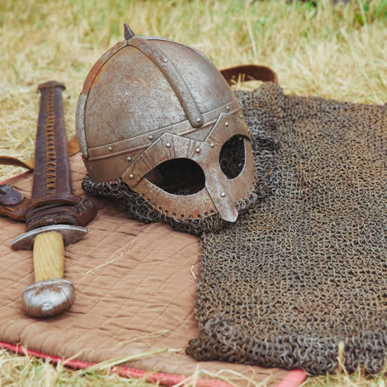 Vikingehjelm og sværd på tæppe i naturen