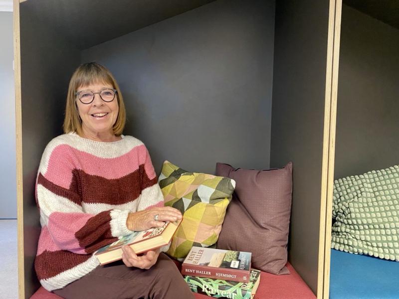 Jytte Albrektsen sidder i en læsehule på biblioteket med favnen fuld af bøger