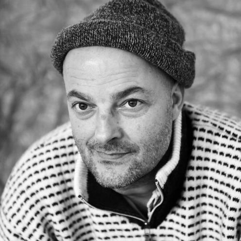 S/H-portræt af Mads Nygaard i striktrøje og med hue.